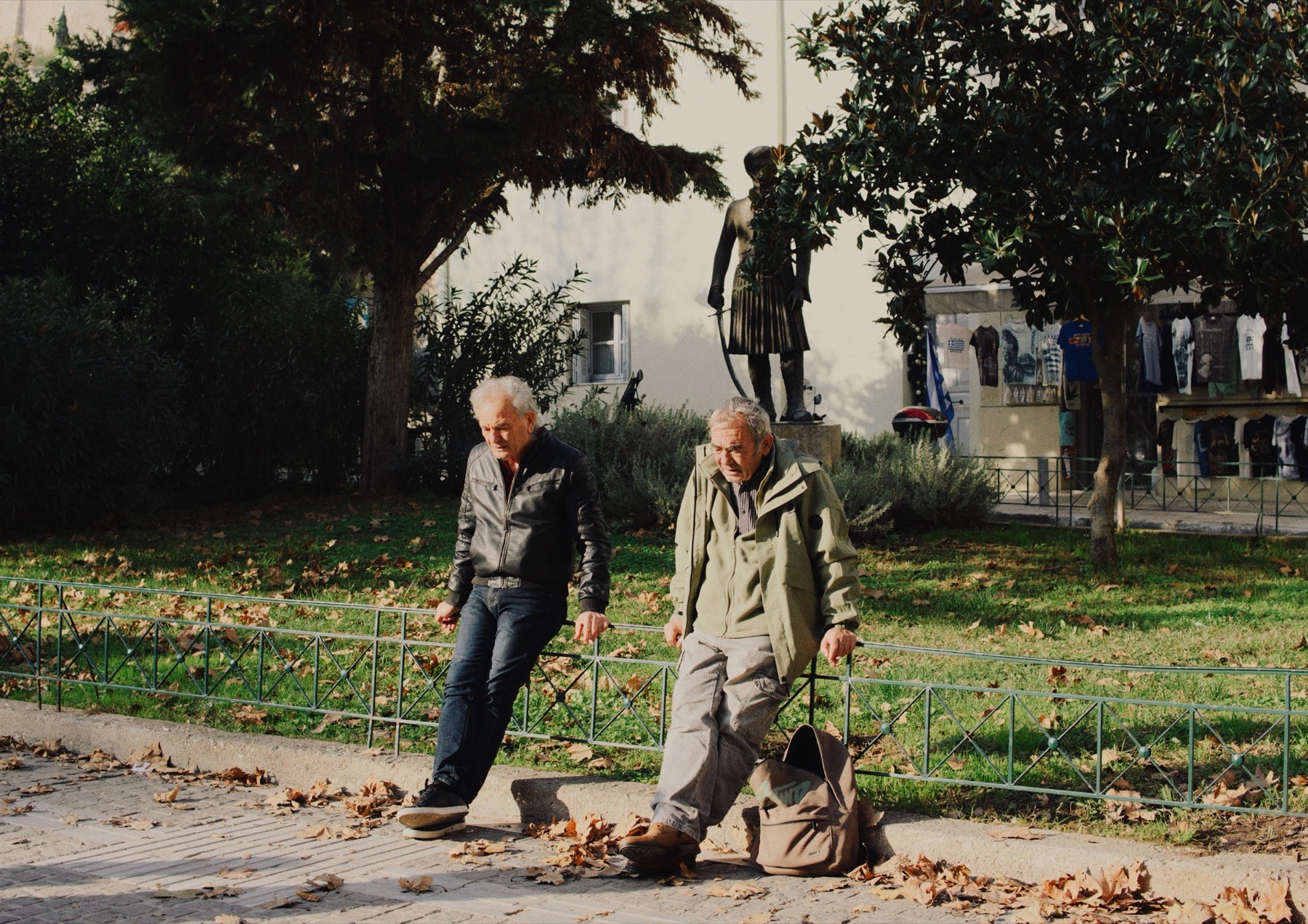 Two older men walking together beneath autumn trees