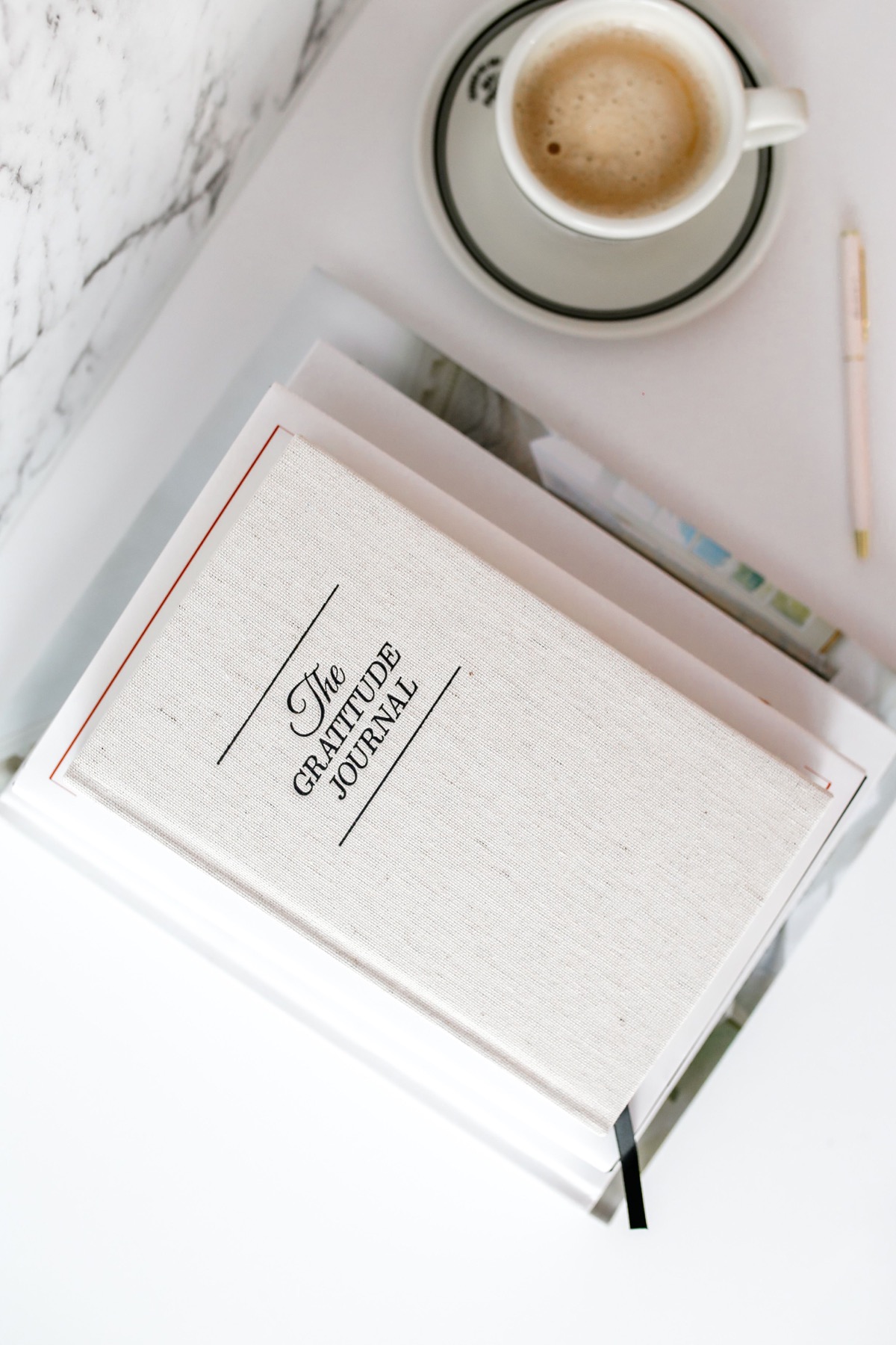 A gratitude journal and a cup of coffee on a desk