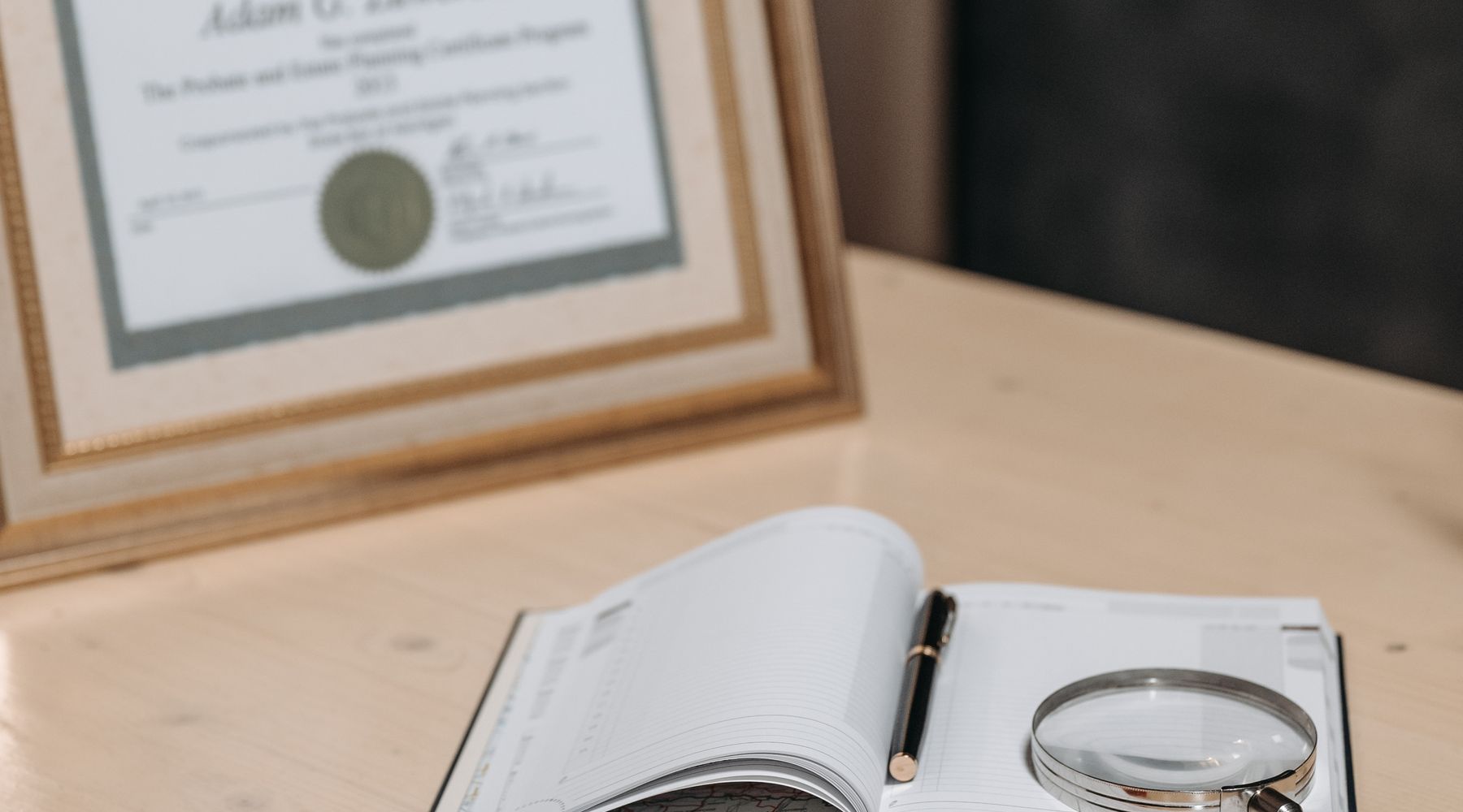 An open notebook and magnifying glass on a desk