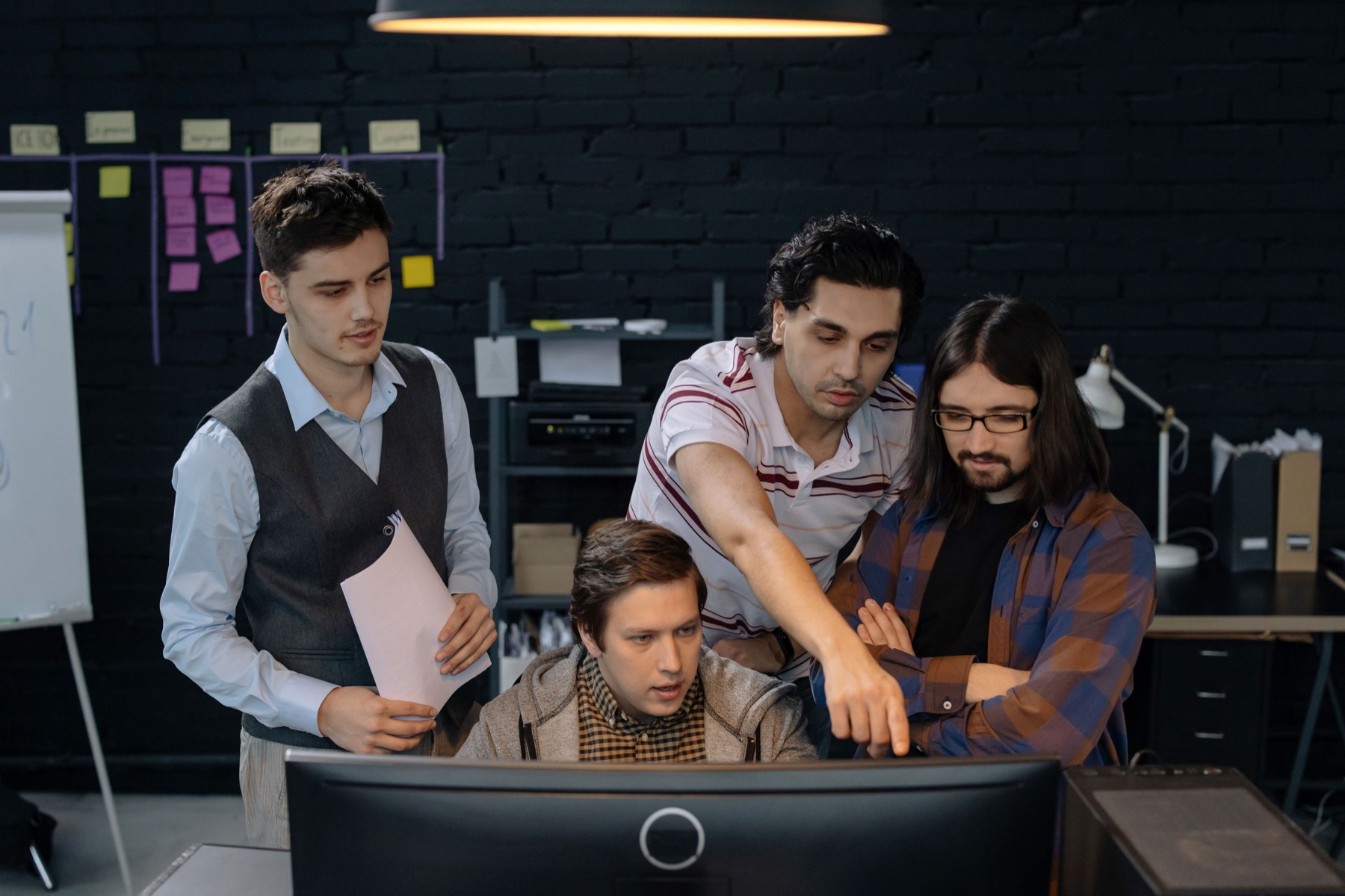 Coworkers collaborate around a computer while planning a project