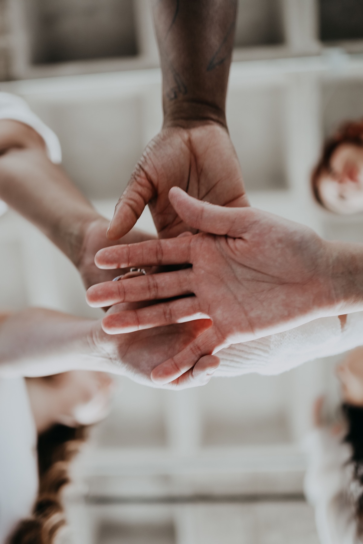 Several people stack their hands together in a gesture of teamwork