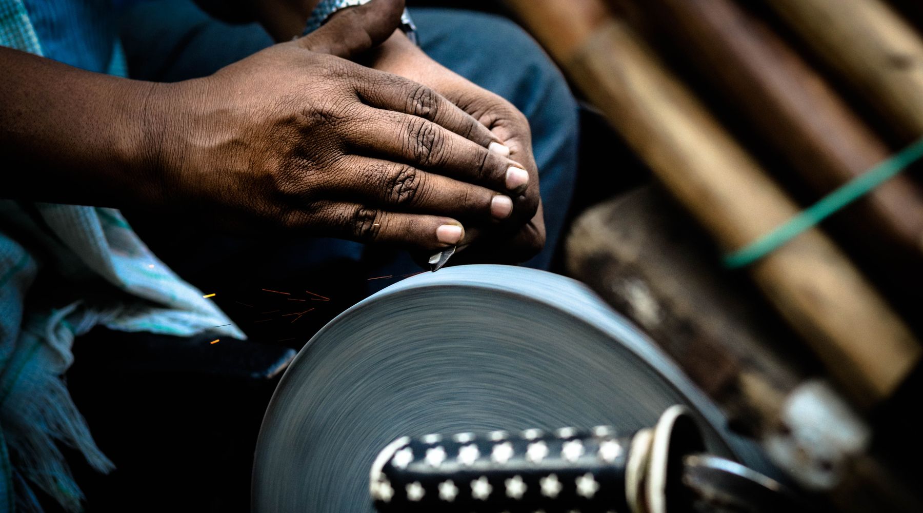 Hands sharpening a knife against a rotating grindstone