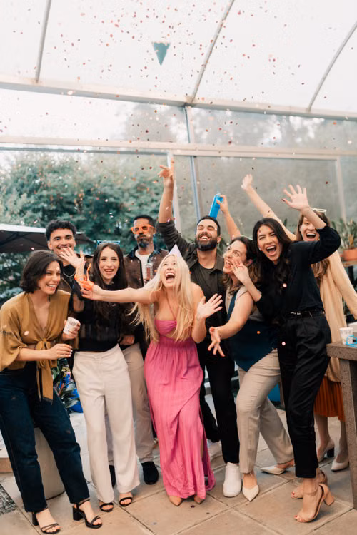 Friends celebrating indoors as confetti falls around them