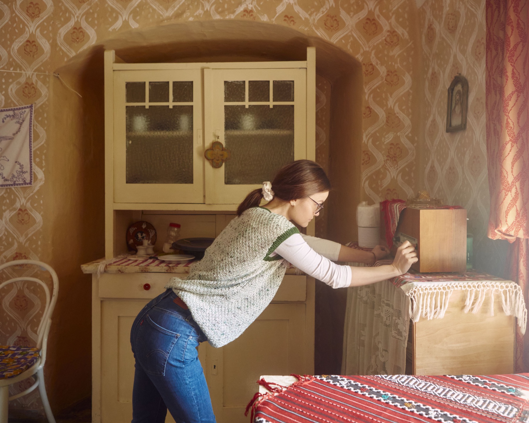 A woman tuning a vintage radio in a cozy room