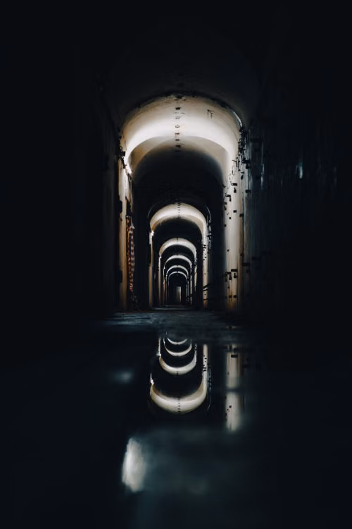 A tunnel with water reflections and light in the distance