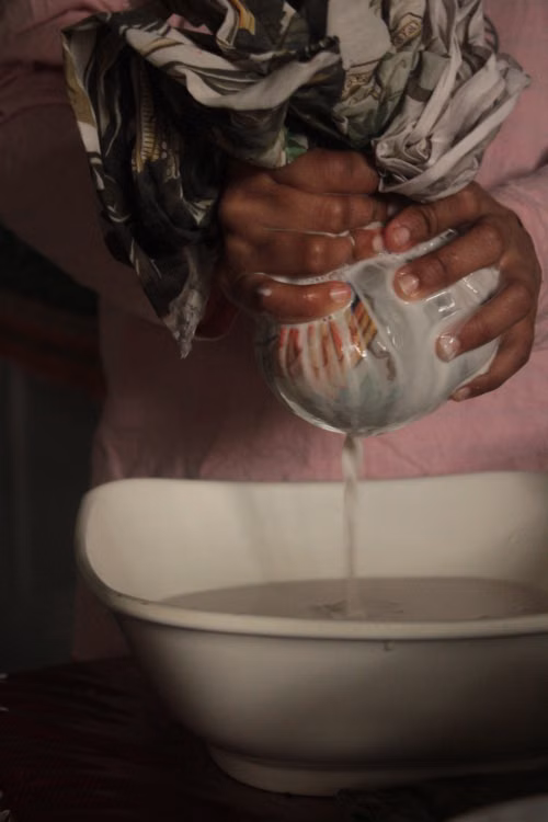 Hands wringing a wet cloth over a bowl